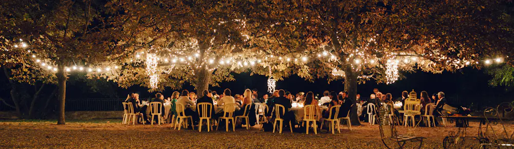 Banquet tables under string lights at night