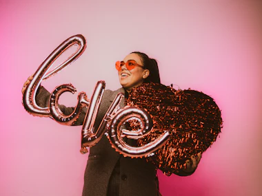 Woman in sunglasses posing with a "love" balloon